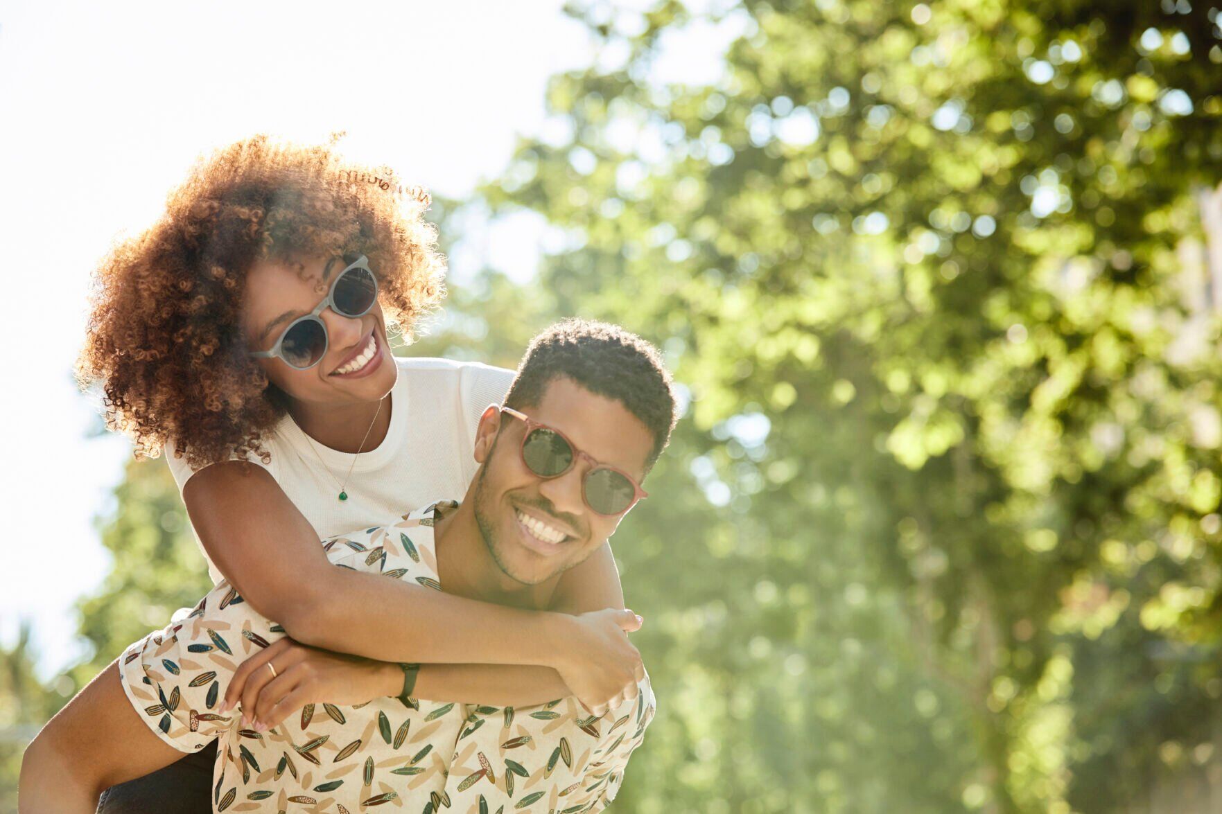 Young couple enjoying piggyback ride on sunny day